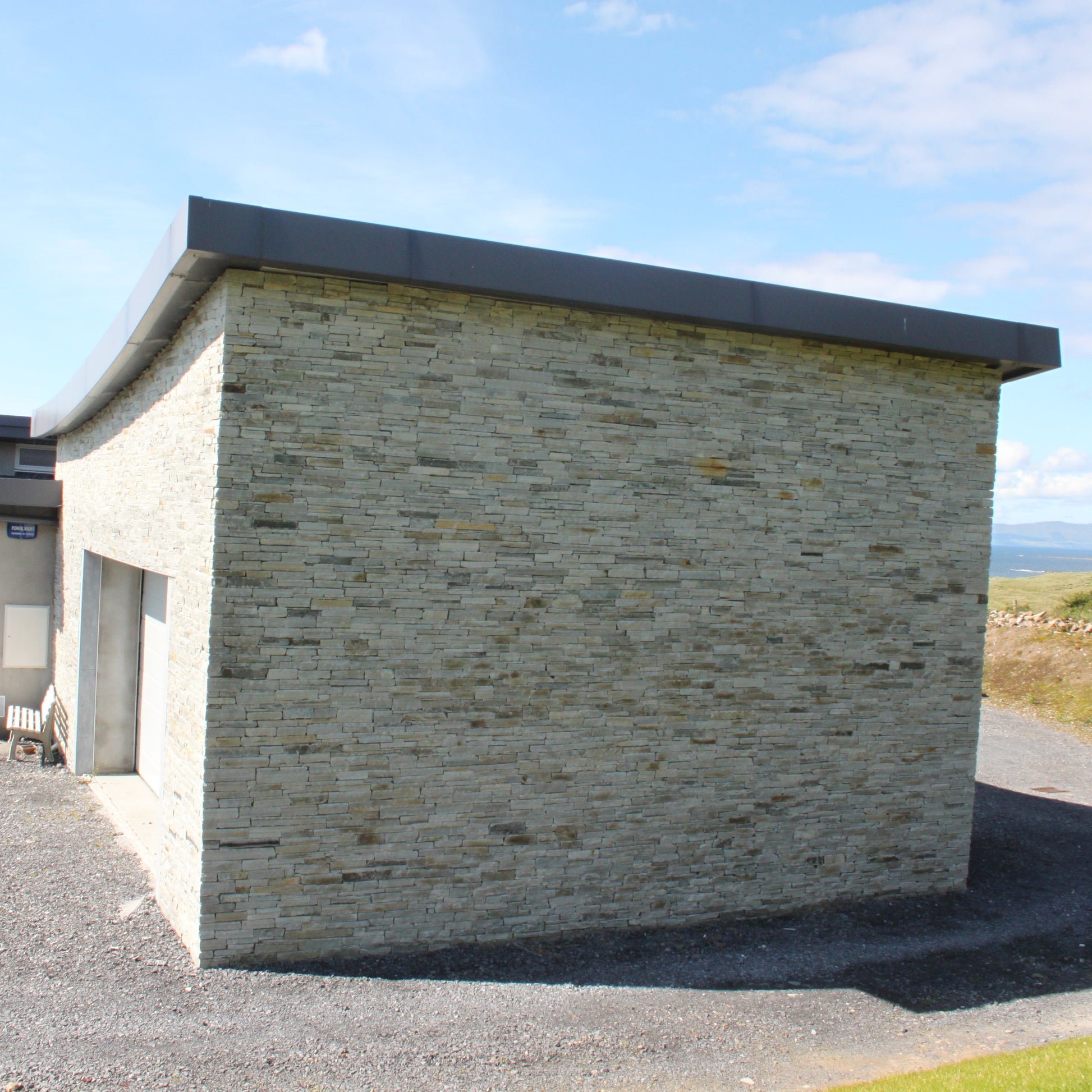 Contemporary garage with natural stone façade in Silver Donegal Quartzite Garden Walling.
