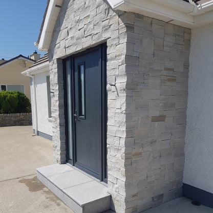 Front porch with grey door. Stone is Silver Donegal Quartzite Stoneer Cladding. 