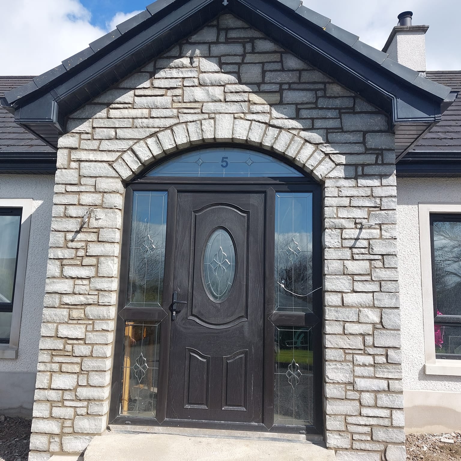 Stone porch with black door completed using Silver Donegal Quartzite Stoneer Cladding. 