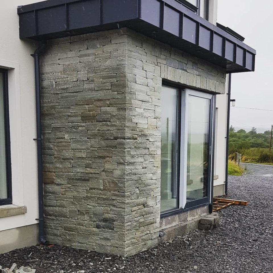 Stone façade with sliding door featuring Silver Donegal Quartzite Stoneer Cladding. 