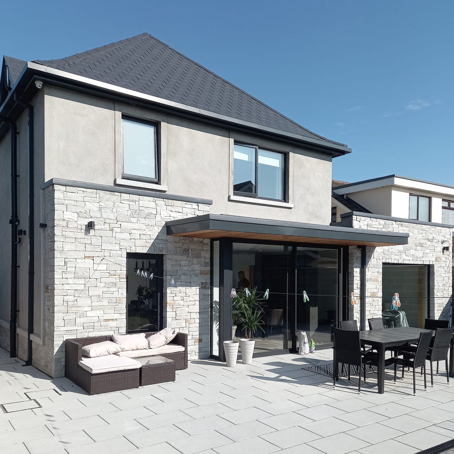 Back of house with outdoor patio area and stonework showcasing Silver Donegal Quartzite Stoneer Cladding.