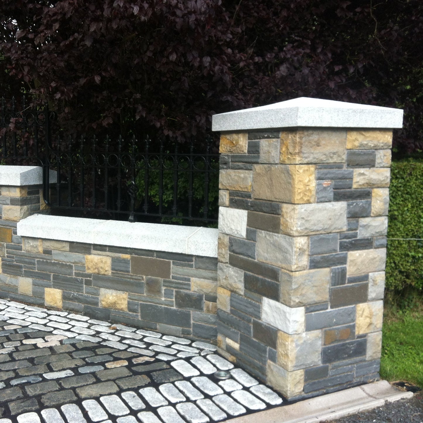 Stone wall with bespoke silver granite apex pillar cap and wall capping. 