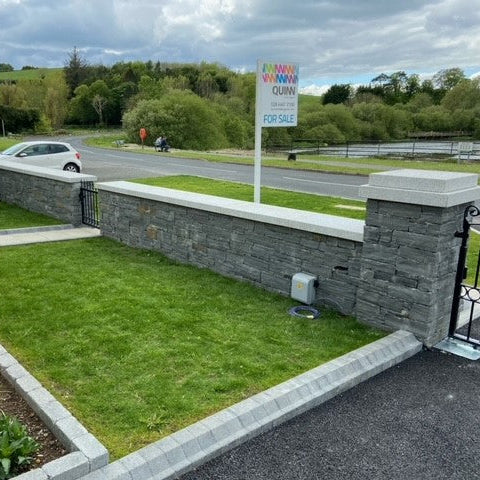 Neatly maintained garden with a stone wall completed with Silver Granite Wall Capping.
