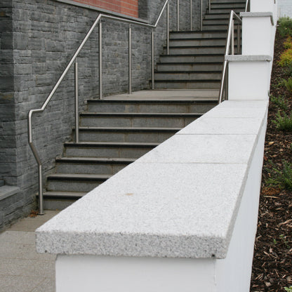 Silver Granite Wall Capping on a wall running alongside steps and a building. 