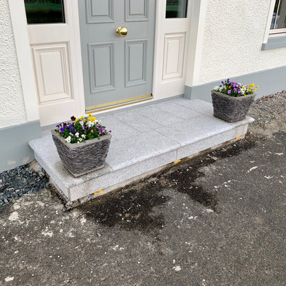 Silver Granite Corner step with flower pots on a driveway in front of a house with a grey door.