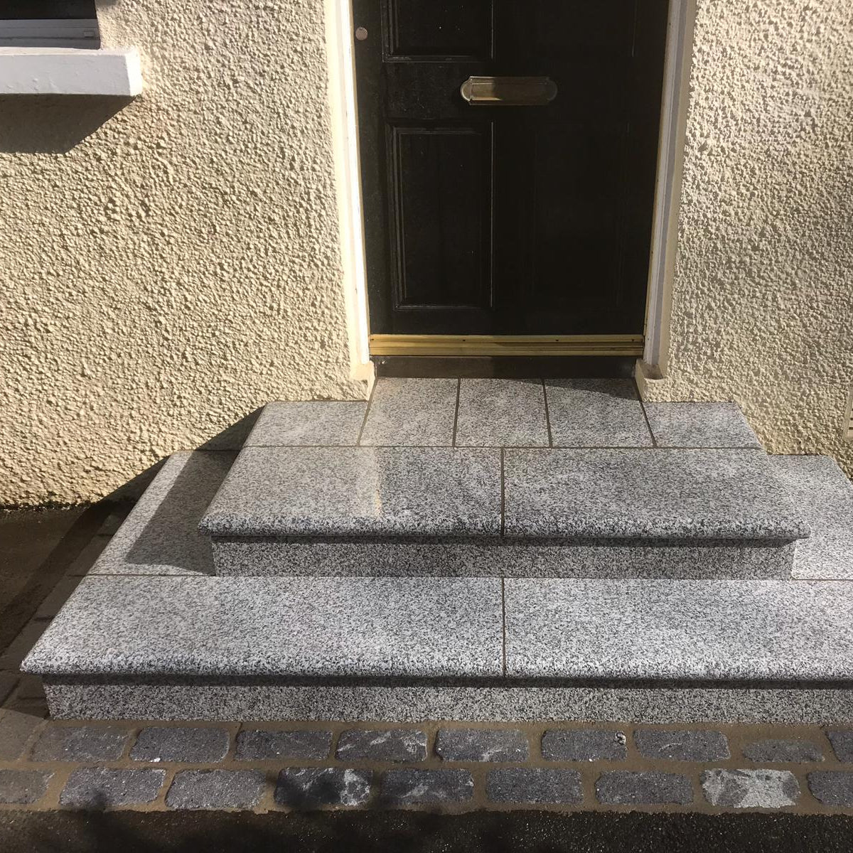 Silver Granite Steps leading up to a black door. 