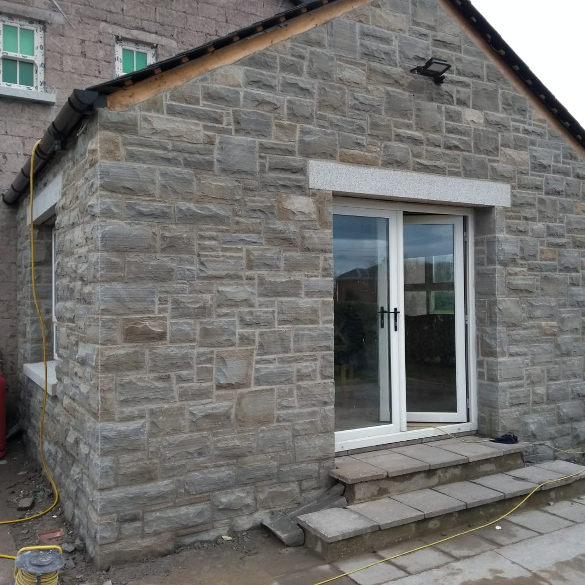 Stone building with a double glass door and bespoke silver granite door lintel. 