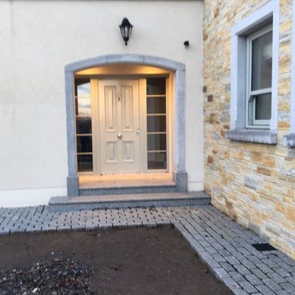 Front entrance of a house with bespoke Silver Granite Door Surround and silver granite steps, cobbles.  