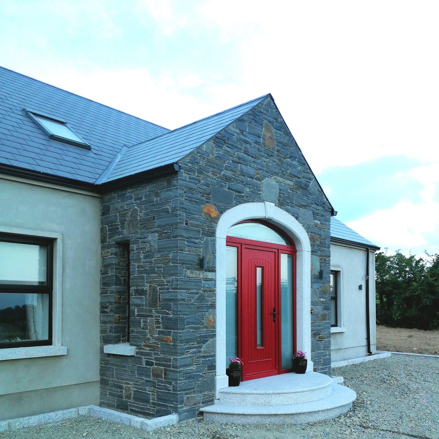 House with a red door and stone facade completed with a bespoke Silver Granite Door Surround, Steps and Sills. 