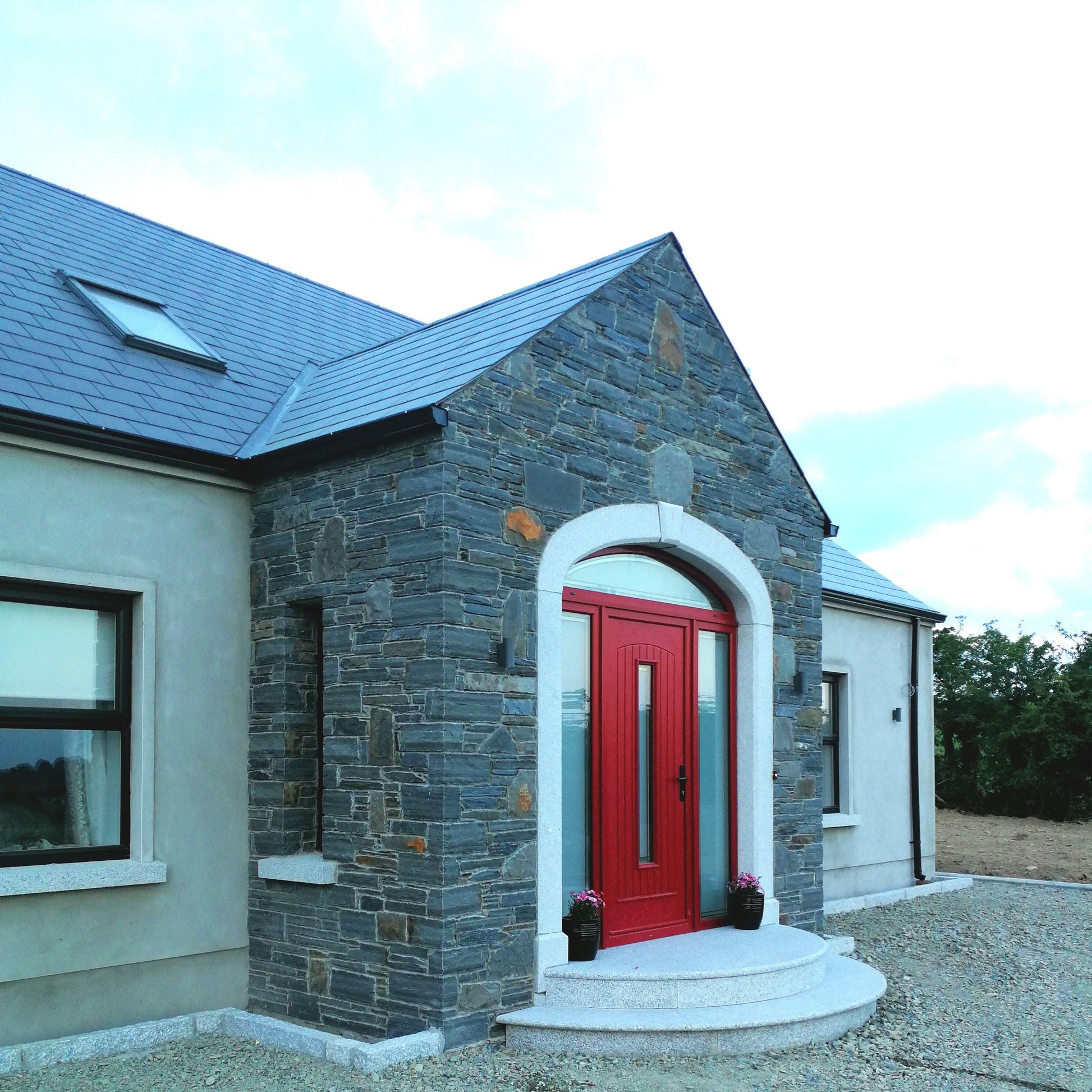 House with a red door and stone facade completed with a bespoke Silver Granite Door Surround, Steps and Sills. 
