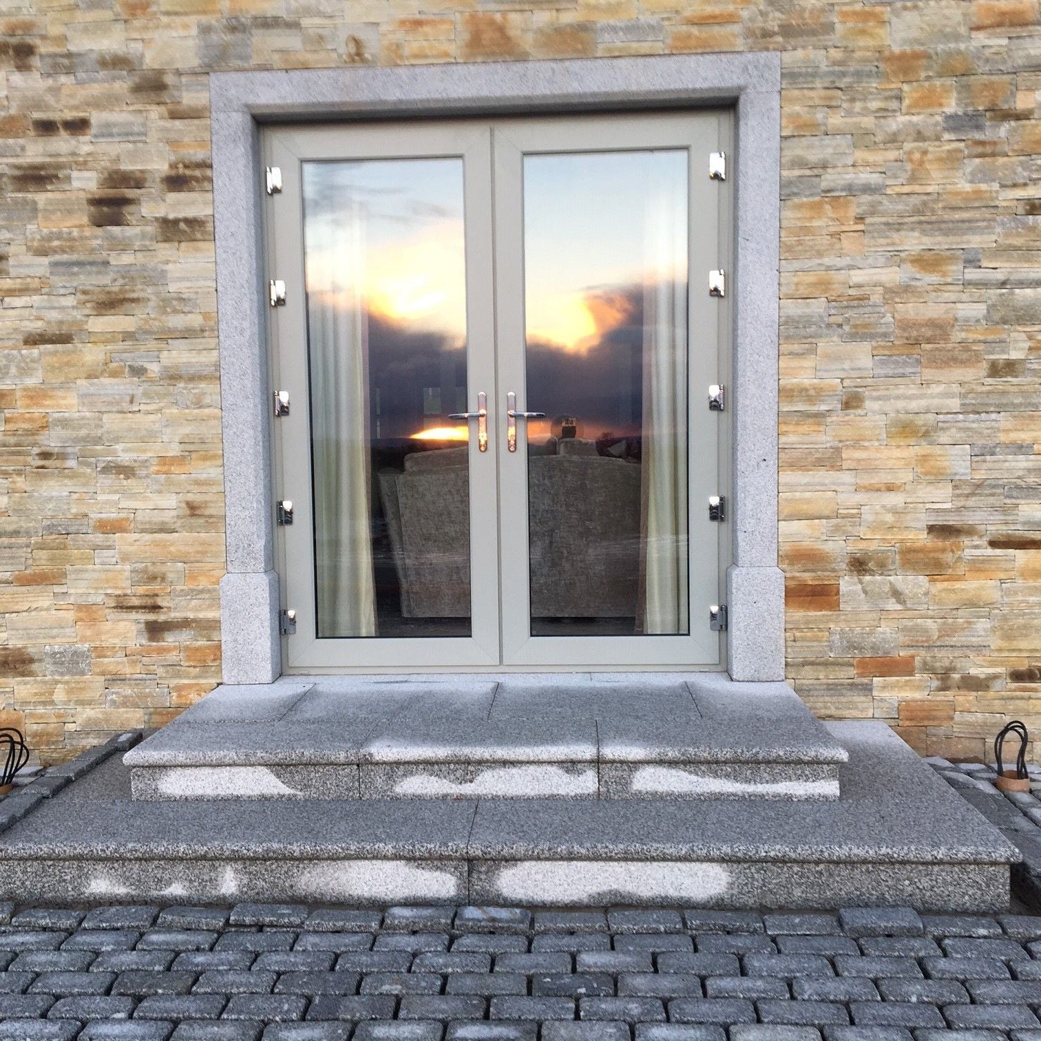 Modern glass door with bespoke silver granite door surround with silver steps and cobbles. 