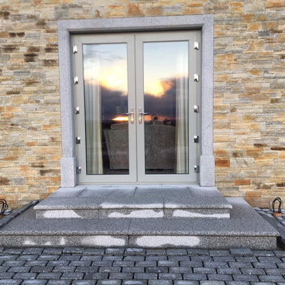 Modern glass door with bespoke silver granite door surround with silver steps and cobbles. 