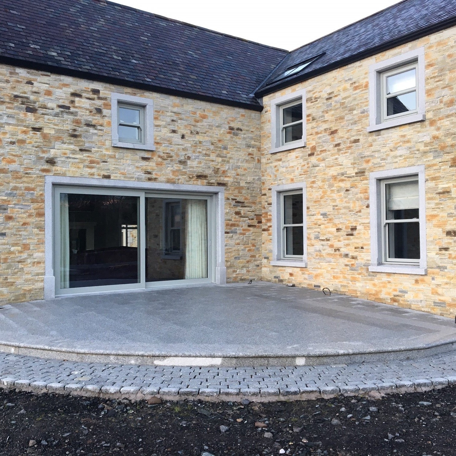 Stone house with silver granite window and door surrounds and a silver granite patio area.