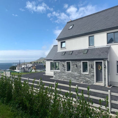 Modern house with a scenic background of water and sky. Porch features bespoke silver granite window and door surround.