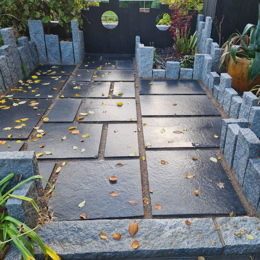 Small patio area featuring black limestone paving and unique plant bed design featuring Silver Granite Kerbs with a pineapple finish. 