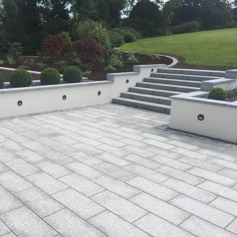 Patio area with steps leading up to garden. Paving is Flamed Silver Granite in 600 x 300mm size. 