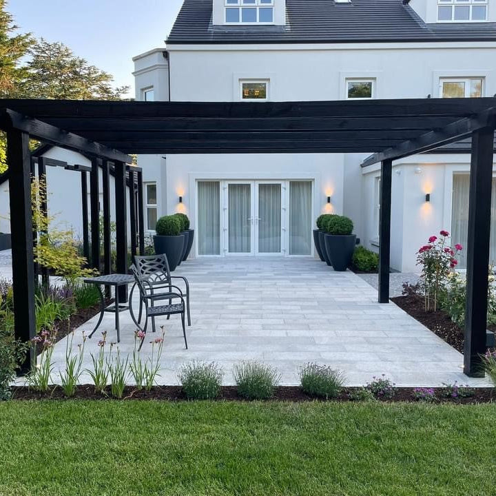 Outdoor patio area featuring Silver Granite Paving in 600x300mm size. Surrounded by grass and planting. 