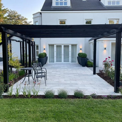 Outdoor patio area featuring Silver Granite Paving in 600x300mm size. Surrounded by grass and planting. 