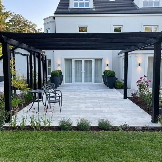 Outdoor patio area featuring Silver Granite Paving in 600x300mm size. Surrounded by grass and planting. 
