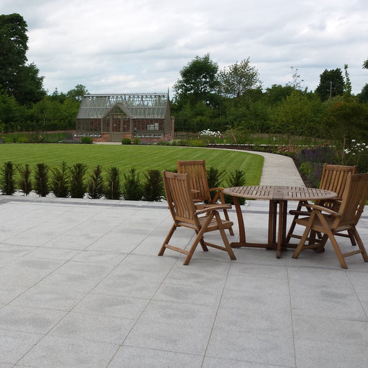 Patio area with pathway leading to greenhouse beyond the garden. Paving is Silver Granite Paving in 600 x 600mm 