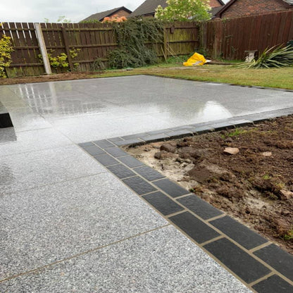 An outdoor installation of Silver Granite Paving in 900 x 600mm size used for a patio area, with the paving stones arranged in a pattern with sawn edges visible.