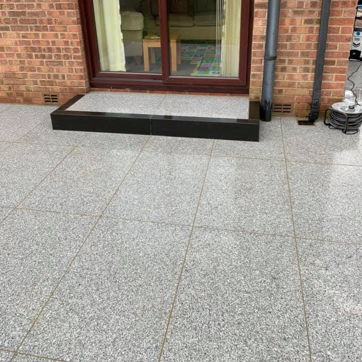 Patio area with step finished with Silver Granite Paving slabs in 900 x 600mm size. 