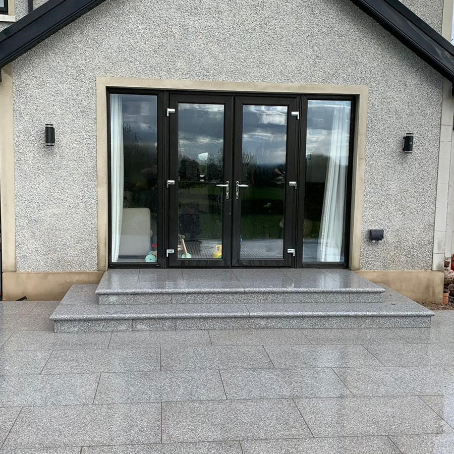 Patio area with steps leading to black double patio doors. Paving is Silver Granite Paving in 900 x 600mm size. 