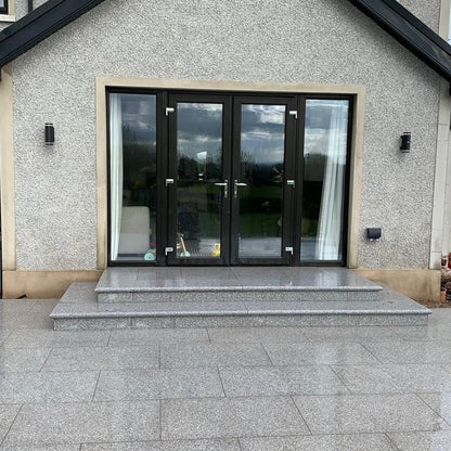 Patio area with steps leading to black double patio doors. Paving is Silver Granite Paving in 900 x 600mm size. 