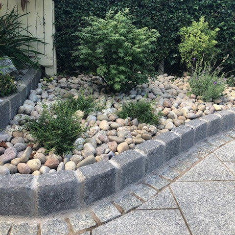 Rockery area with planting featuring natural stone products. Silver Granite Paving Cobbles are used as a border between the kerbing stone and paving. 