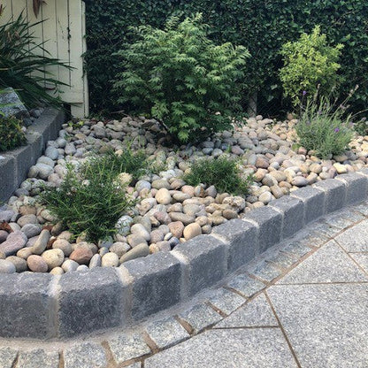 Rockery area with planting featuring natural stone products. Silver Granite Paving Cobbles are used as a border between the kerbing stone and paving. 