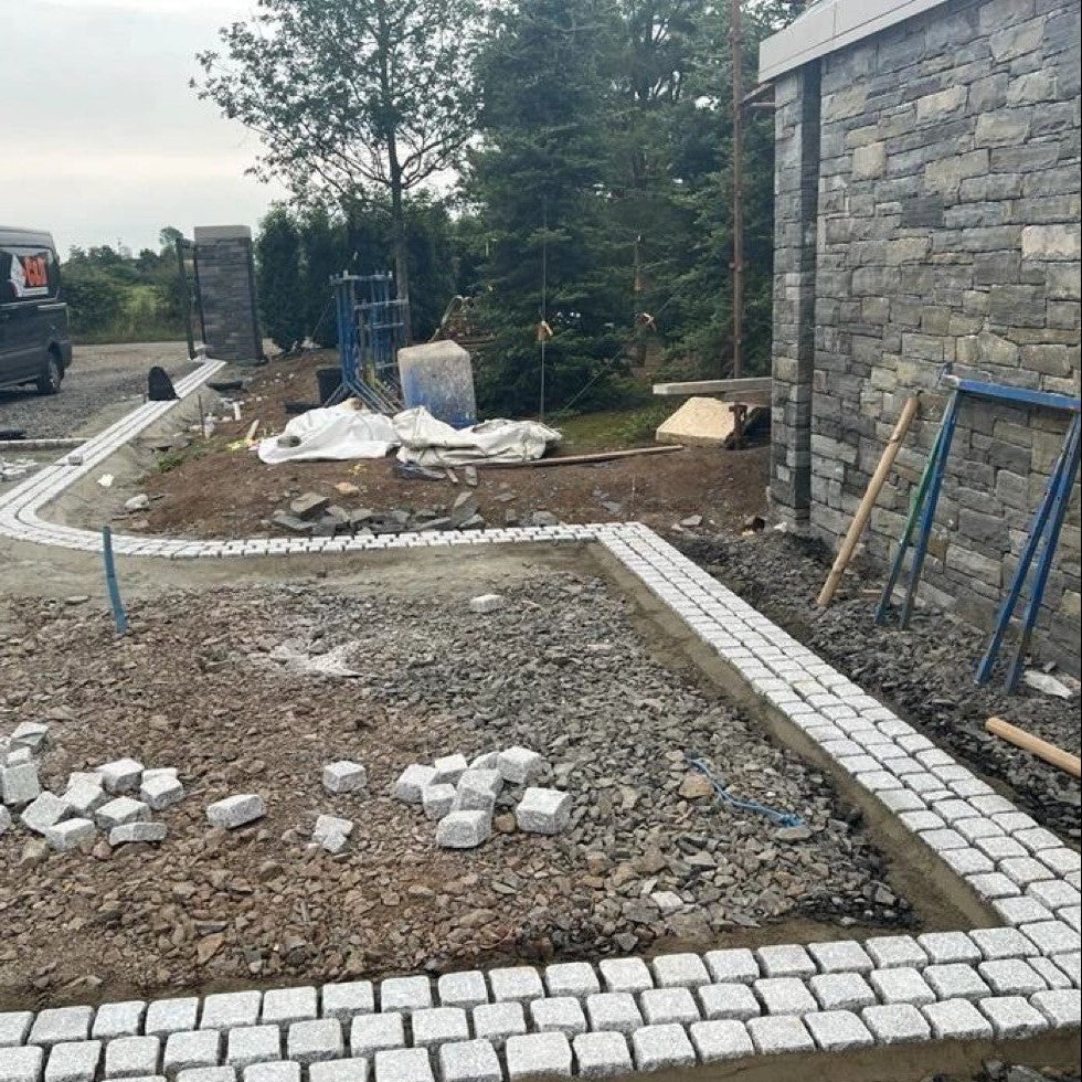 Construction site with driveway border nearing completion using triple row of Silver Granite Cobbles in 100 x 100mm size. 