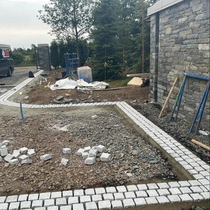 Construction site with driveway border nearing completion using triple row of Silver Granite Cobbles in 100 x 100mm size. 