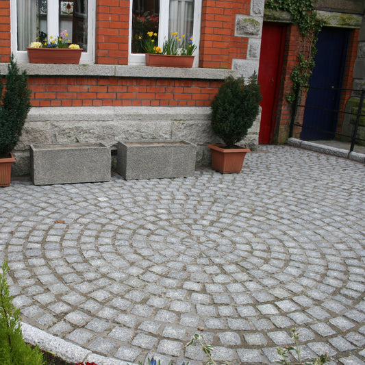 Patio area featuring Silver Granite Paving Cobbles in 100 x 100mm installed in a circular design. 