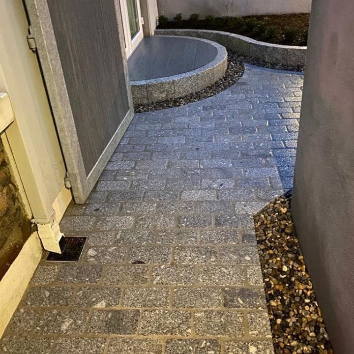 Paved pathway leading to a building entrance with a small patio area completed using Silver Granite Cobbles in 200 x 100mm size. 