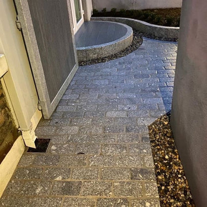 Paved pathway leading to a building entrance with a small patio area completed using Silver Granite Cobbles in 200 x 100mm size. 