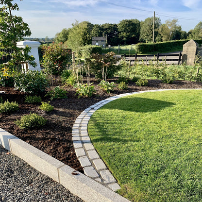 Garden edging separating plants from grass using Silver Granite Paving Cobbles. 