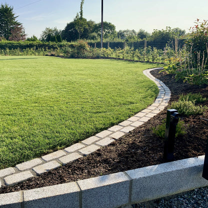 Lawn with a curved stone garden edging completed using Silver Granite Cobbles and garden beds. 