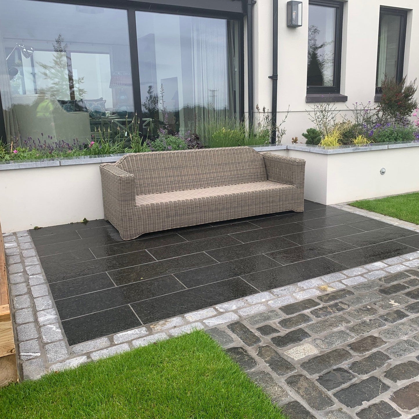 Paved seating area with mixed paving materials. Bordering the patio paving is a double row of Silver Granite Cobbles in 200 x 100mm size. 