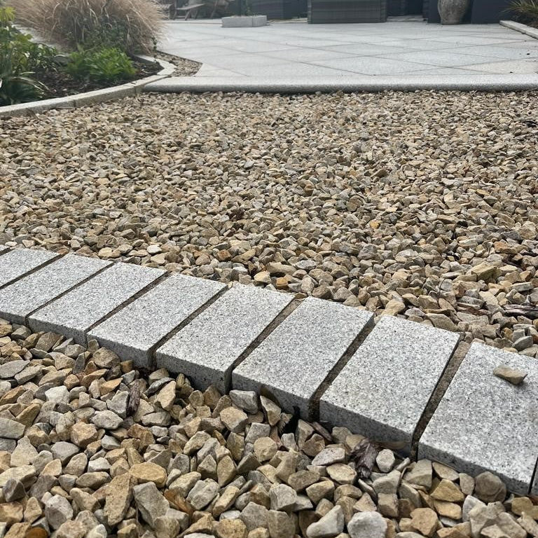 Close up of Sawn Silver Granite Cobbles with a flamed finish on a stone pathway in a garden setting.
