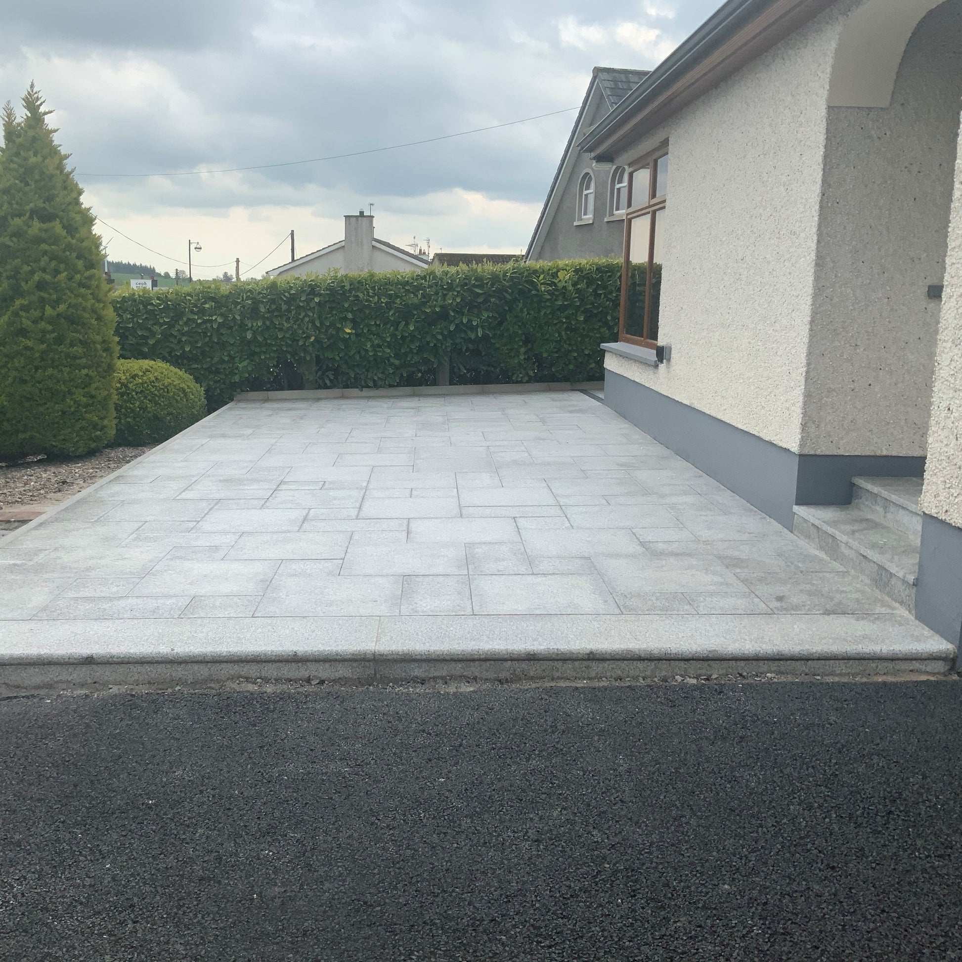 Patio area to the front of a house featuring Silver Granite Paving in mixed sizes. 