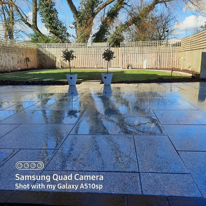 Silver Granite Paving Patio Packs photographed wet on patio area with garden at the end. 