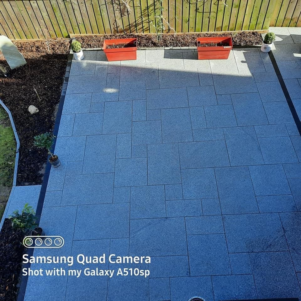 Silver Granite paver patio with garden beds and plants in a backyard. setting.