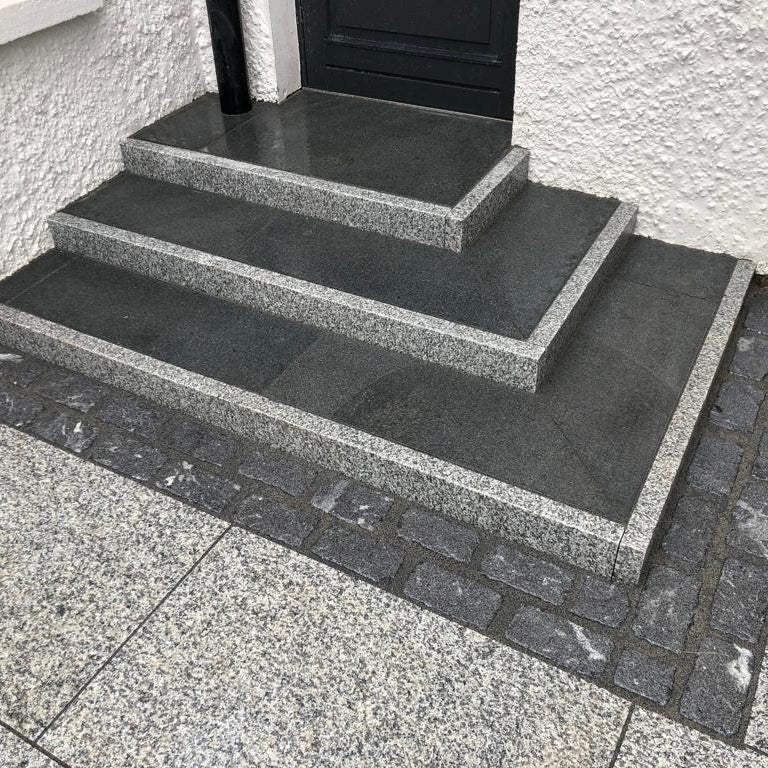 Set of stone steps leading up to a door on a building exterior. Steps completed using Silver Granite Pin Kerbs. 