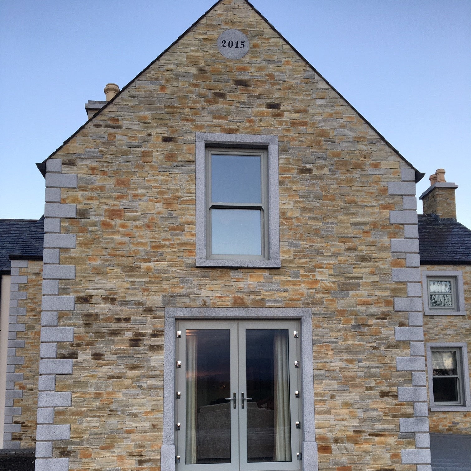 Stone building with a modern door and window design with bespoke Silver Granite Plaque with the year 2015 engraved to mark the year the house was constructed.