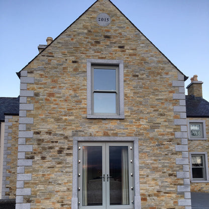 Stone building with a modern door and window design with bespoke Silver Granite Plaque with the year 2015 engraved to mark the year the house was constructed.