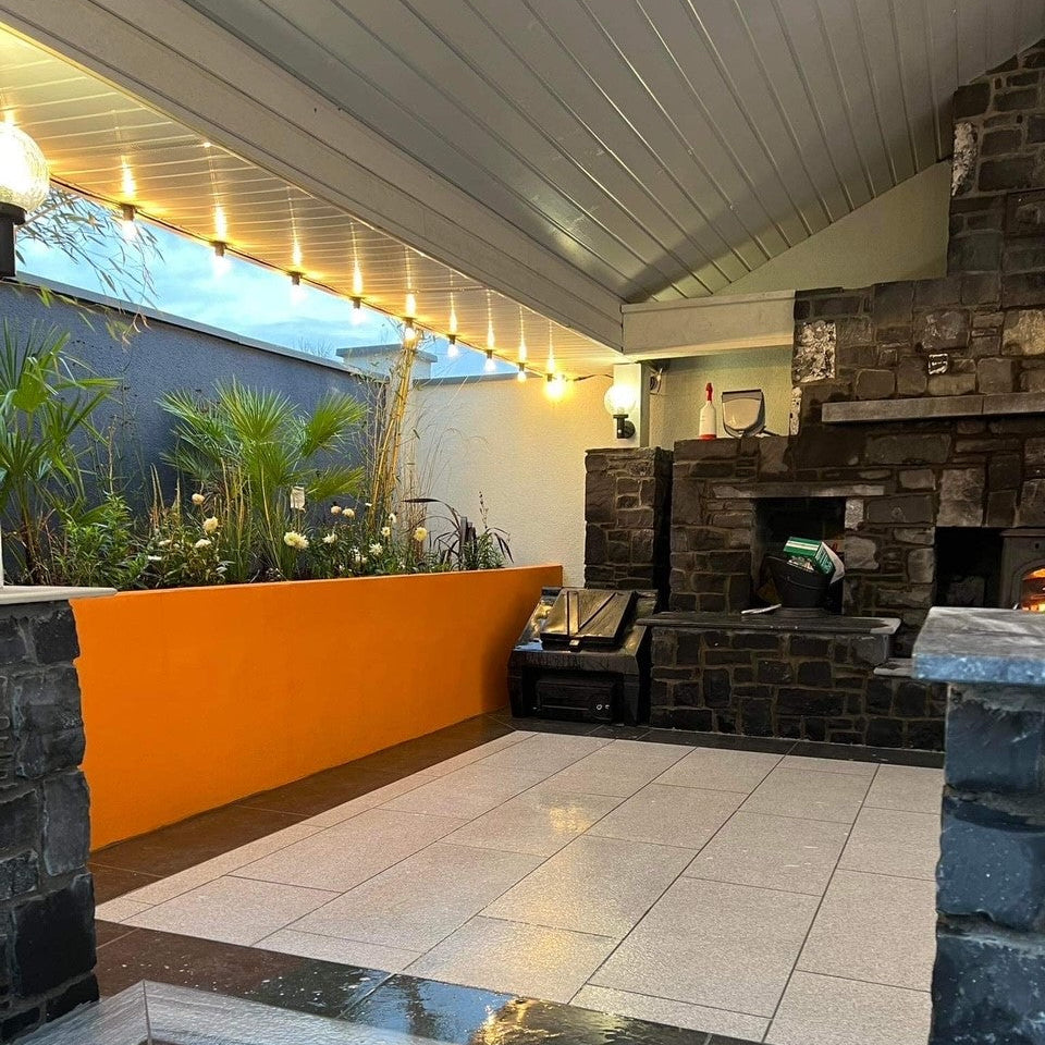 Outdoor living space with roof, large fireplace and Silver Granite Porcelain Paving Tiles. 