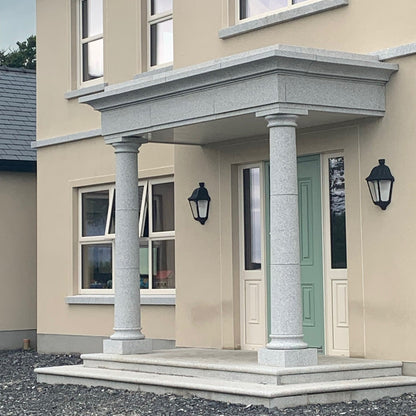 Neatly maintained house exterior with a green door and decorative Silver Granite Portico. 