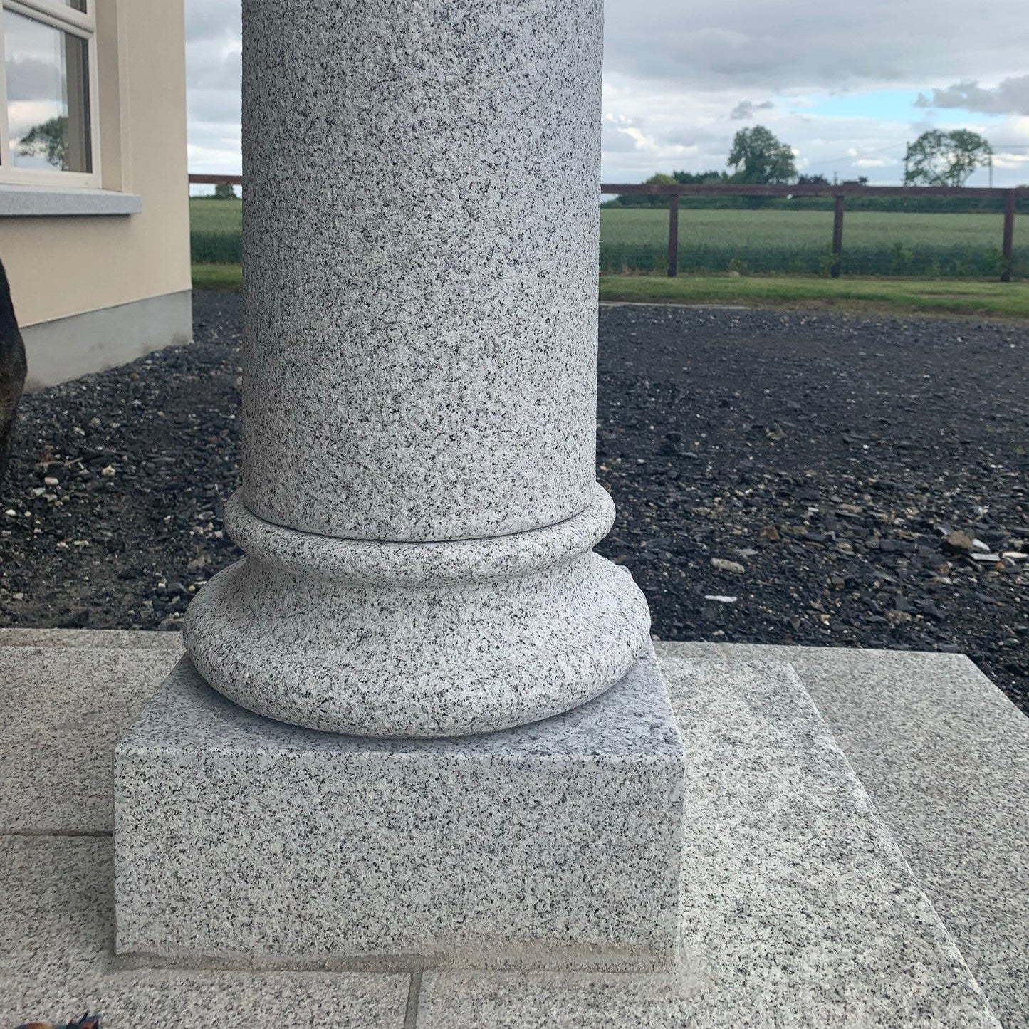 Granite column in front of a building with a cloudy sky and landscape in the background