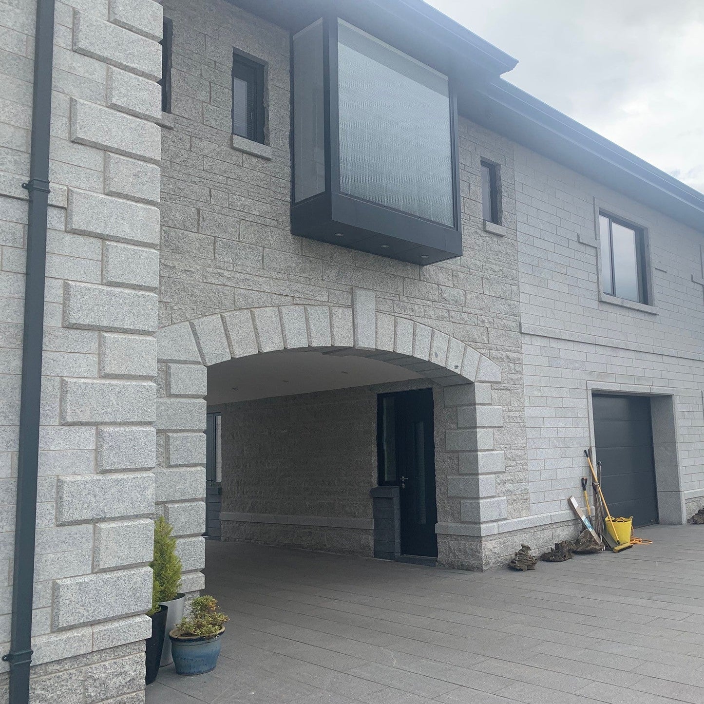 Modern house exterior with stone façade and garage doors. Featuring Bespoke Silver Granite Quoins.