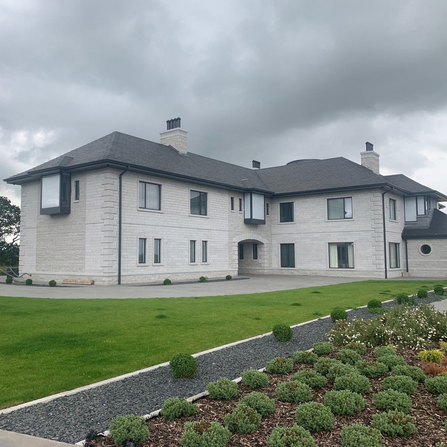 Modern house with gray roof and white walls on a cloudy day